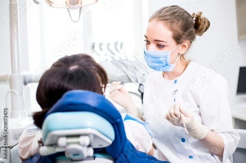 Girl dentist treats the patient's teeth lying in the dental chair in the clinic