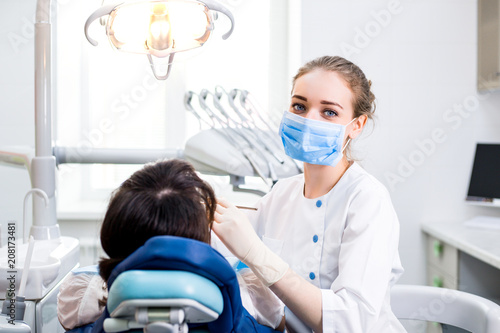 Dentist in Uniform Treats the Teeth of a Patient Lying in a Dental Chair