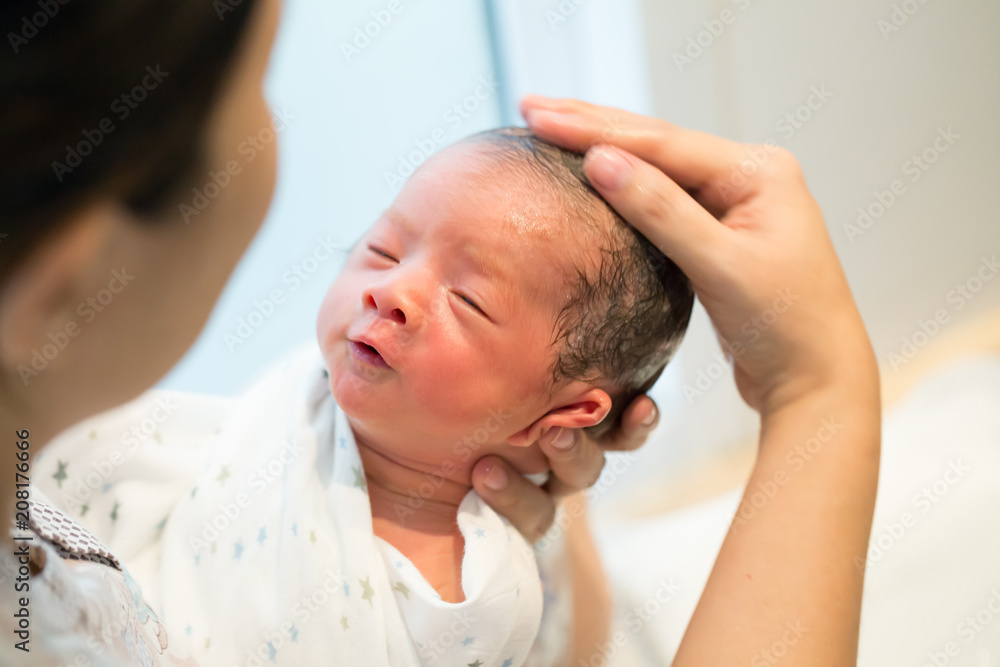 Fototapeta premium Mother giving her baby first bath, Bathing newborn concept