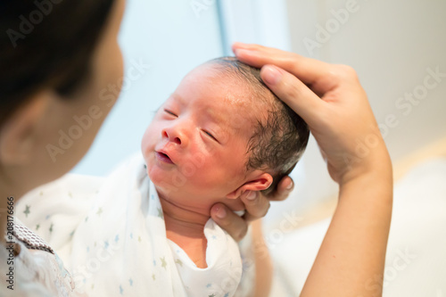 Mother giving her baby first bath, Bathing newborn concept