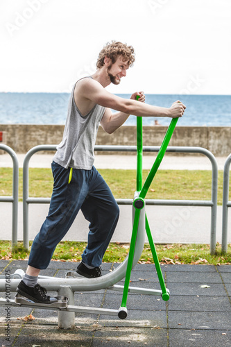 Active man exercising on elliptical trainer.