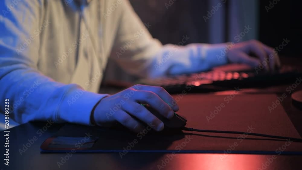 Close-up addiction guy with manly hands playing video game on computer screen with fingers on keyboard. Selective focus on a hand with mouse Close-up addiction guy with manly hands playing video game on computer screen with fingers on keyboard. Selective focus on a hand with mouse