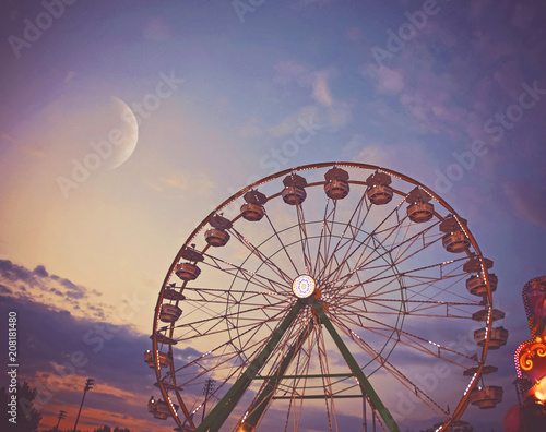 people riding rides and enjoying the summer atmosphere at a state fair at dusk toned with a retro vintage filter app or action