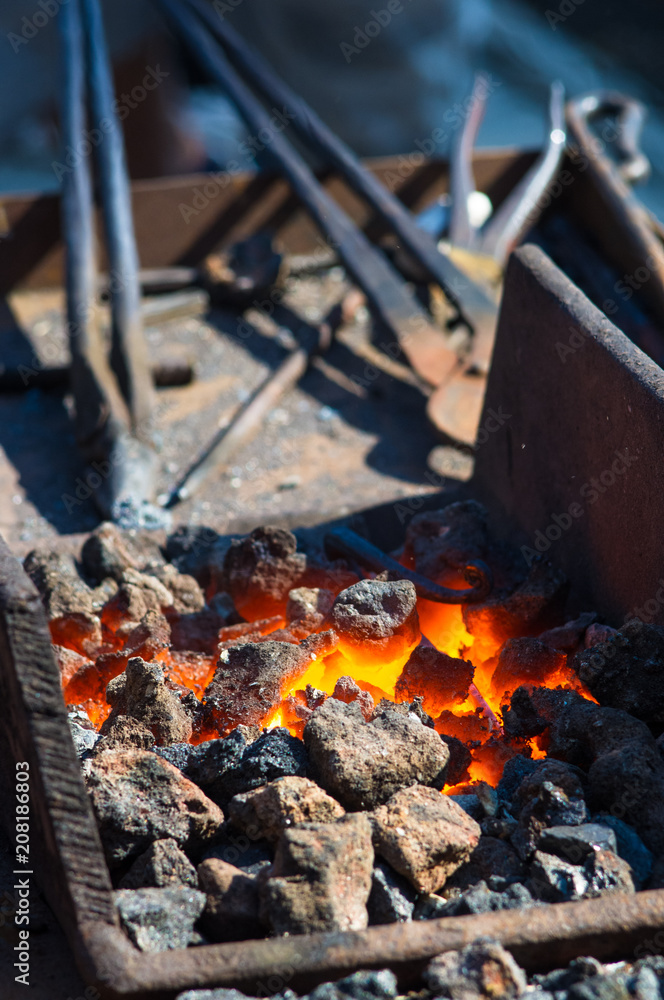 blacksmith furnace with burning coals, tools, and glowing hot metal workpieces
