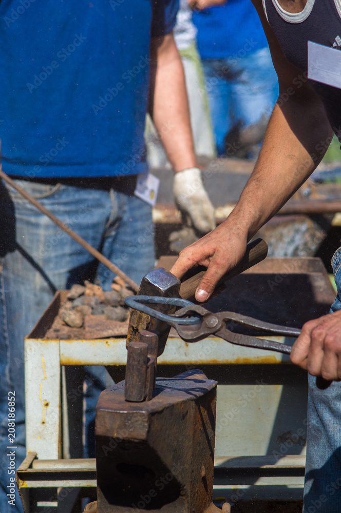 blacksmith performs the forging of hot glowing metal on the anvil