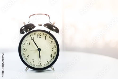 Black alarm clock on white table background