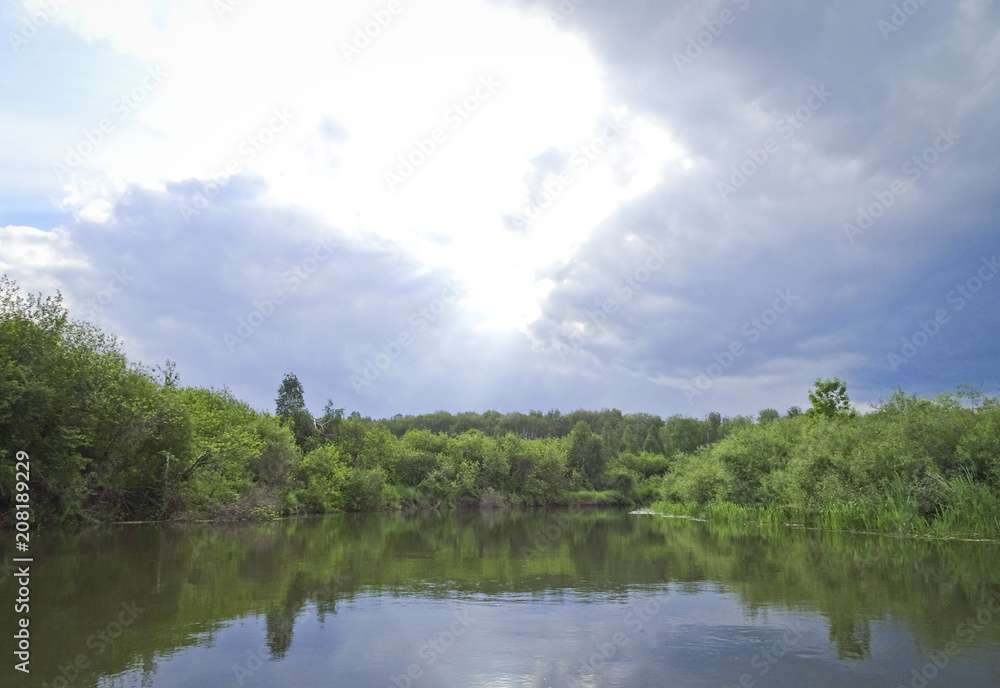 Summer landscape: calm river and storm clouds