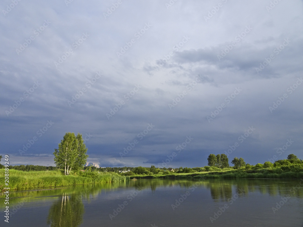 Summer landscape: calm river and storm clouds