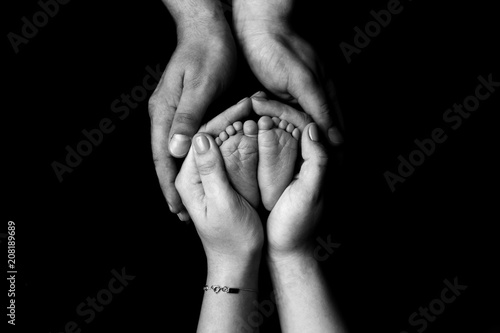 Hands hold newborn feet