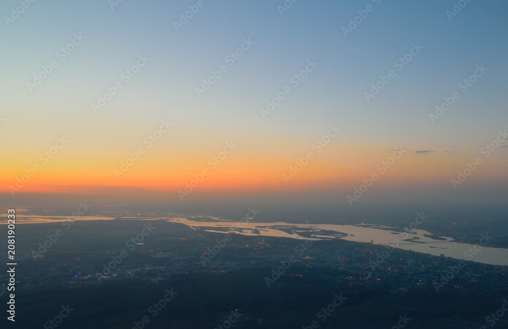 from the height of the bird's flight, the morning dawn, the sunrise over the banks of the Volga River, and urban buildings, against a background without a cloudy sky, Saratov, Russia.