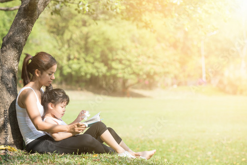 Mother and daughter relaxing in park.She reading a fairytale to her daughter