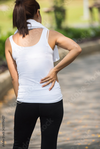 Sports injury - Lower back pain woman holding body touching painful waist muscles showing smartwatch on wrist..