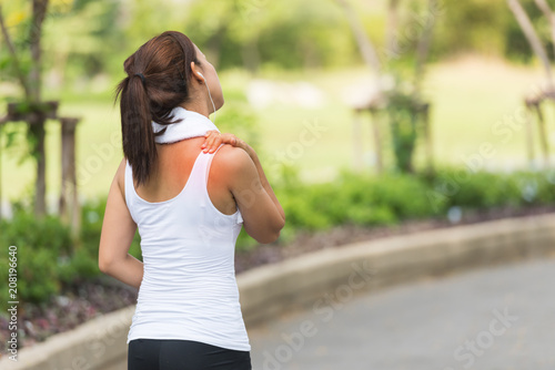 Neck pain during training. Athlete running woman runner with sport injury rubbing and touching upper back muscles outside after exercise workout in summer.