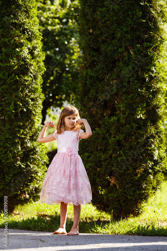 Portrait of a girl in a lush pink dress in the park.