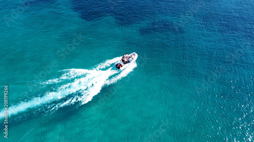 Aerial drone bird's eye view photo of small boat cruising in tropical emerald clear waters © aerial-drone