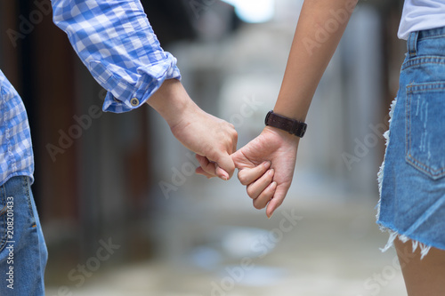 Happy couple holding hands pinky promise or pinky swear. Man woman in love trust and support together.Conceptual image of female and male hands together romance relationship.