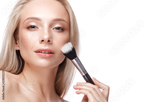 Beautiful young girl with a light natural make-up,brushes for cosmetics and nude manicure. Beauty face. Picture taken in the studio on a white background.