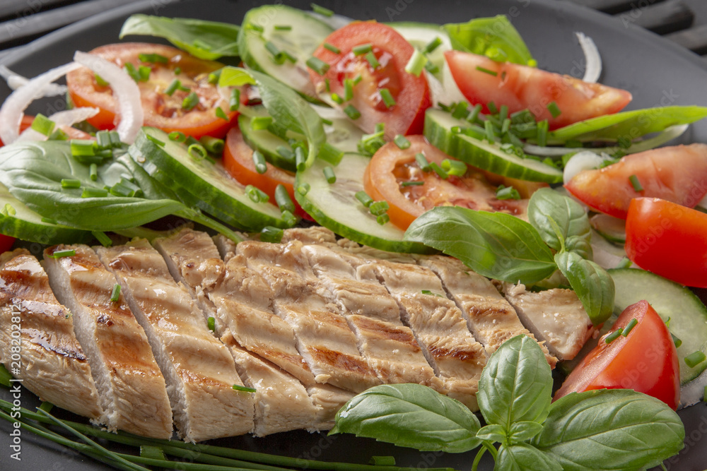 Vegetable salad and grilled chicken on a black background. Healthy food. Diet. Vegetable salad and grilled chicken on a black background. Healthy food. Diet.