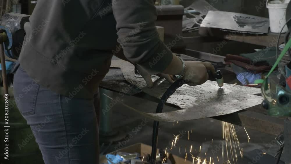 Woman blacksmith cutting aluminum shapes with plasma cutter in her workshop Woman blacksmith cutting aluminum shapes with plasma cutter in her workshop