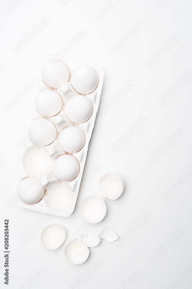 top view of raw chicken eggs in carton on white surface