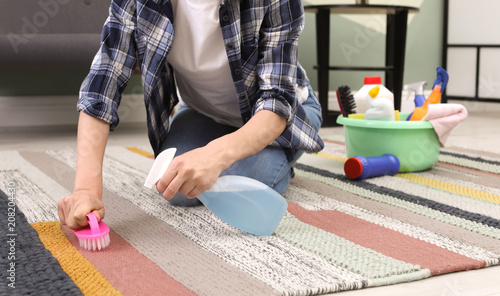 Woman cleaning carpet with brush at home