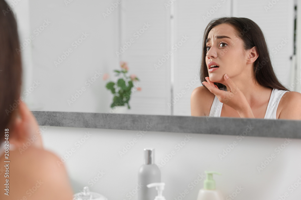 Young woman with eyelash loss problem looking in mirror indoors Young woman with eyelash loss problem looking in mirror indoors