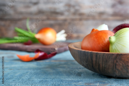 Plate with fresh ripe onions on wooden table