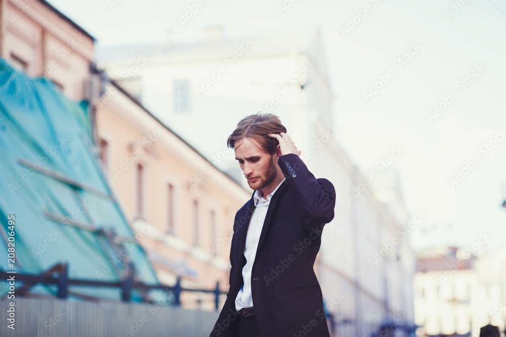stylish man in a suit stands against a background of city buildings stylish man in a suit stands against a background of city buildings