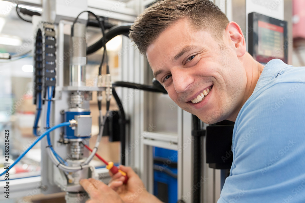 Portrait Of Male Engineer Working On Machine In Factory Portrait Of Male Engineer Working On Machine In Factory
