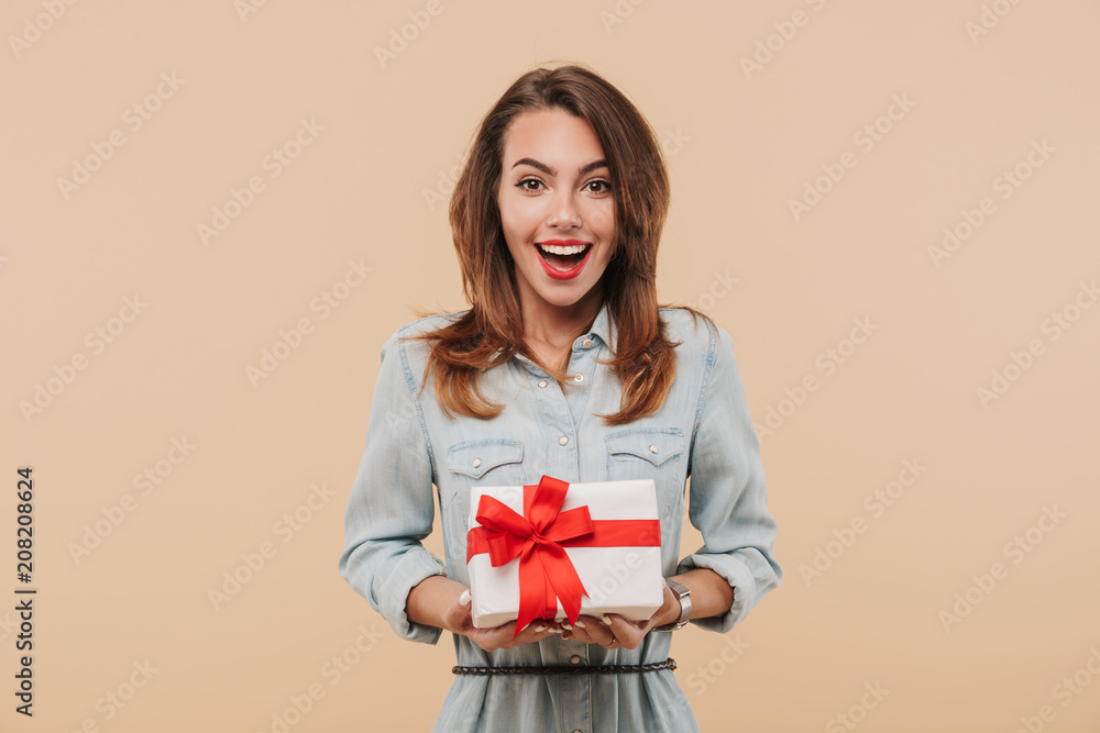 Fototapeta premium Portrait of an excited young girl holding present box