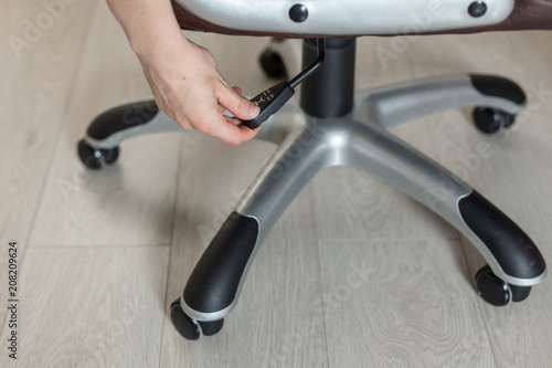 Fotografija The girl adjusts the height of the new brown office chair