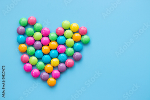 Sweet candy heart shape onblue background. Love dessert concept with copy space