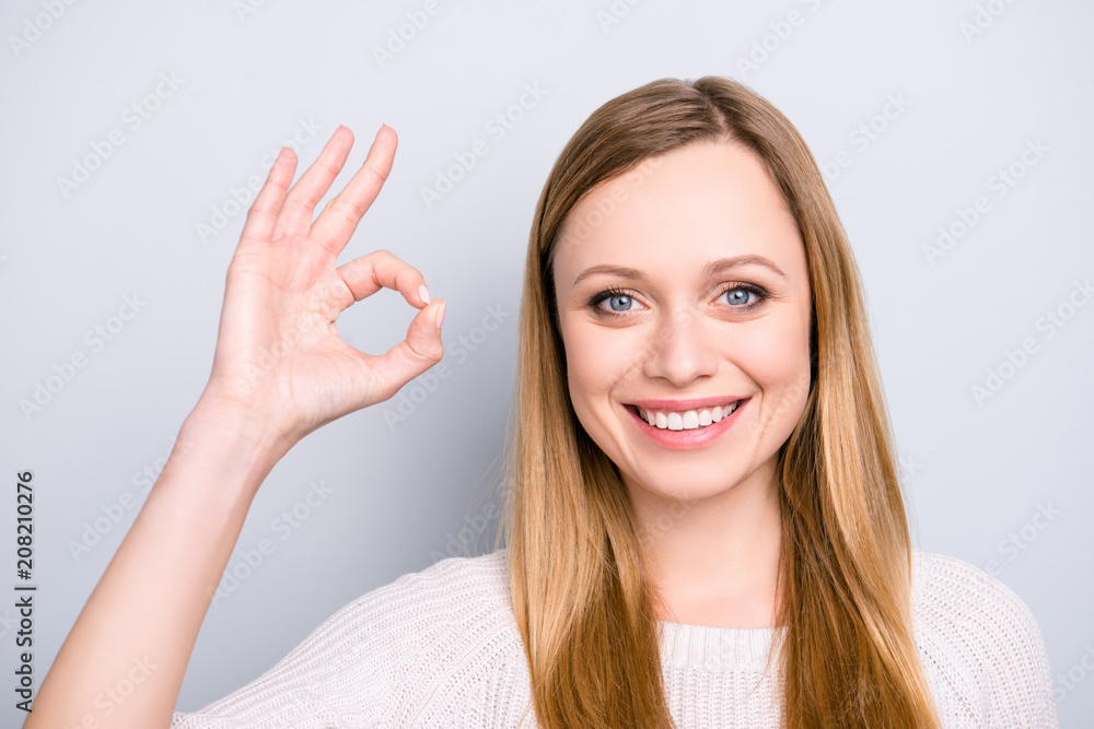 Head shot portrait of positive stylish girl with beaming smile gesturing ok sign with fingers looking at camera isolated on grey background Head shot portrait of positive stylish girl with beaming smile gesturing ok sign with fingers looking at camera isolated on grey background