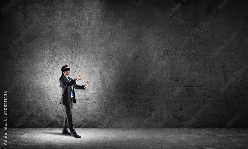 Business concept of risk with businessman wearing blindfold in empty concrete room Business concept of risk with businessman wearing blindfold in empty concrete room