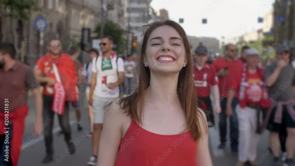 Portrait of young charming woman standing on street during festival and turning her head, smiling, crowd walking around her Portrait of young charming woman standing on street during festival and turning her head, smiling, crowd walking around her