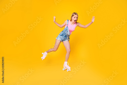 Portrait of nervous yelling girl learning roller skating afraid to ride trying not to fall down isolated on yellow background, street outside urban activity concept