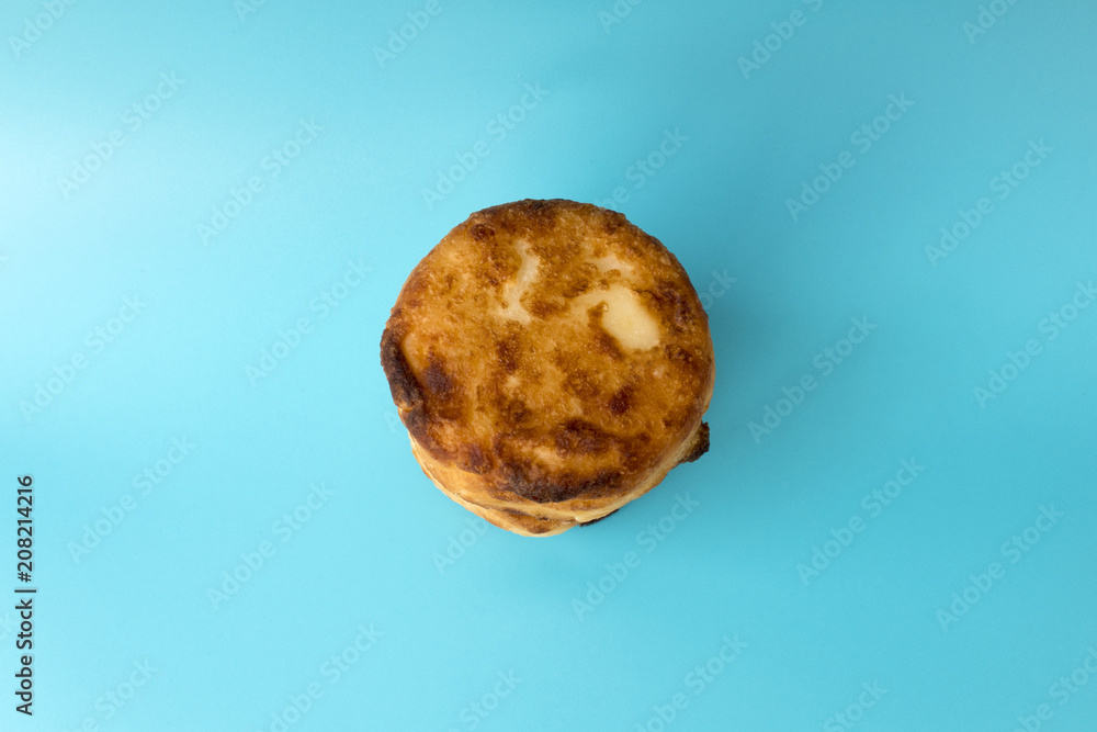 Traditional dish cooked from curd flour and eggs fried syrniki closeup on a blue background Traditional dish cooked from curd flour and eggs fried syrniki closeup on a blue background