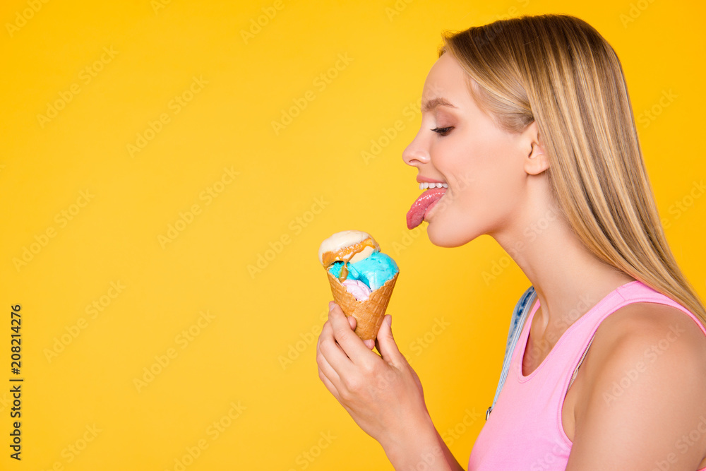 Profile half face portrait with copy space empty place for advertisement of naughty seductive girl licking caramel vanilla ice cream gesturing showing tongue out isolated on yellow background Profile half face portrait with copy space empty place for advertisement of naughty seductive girl licking caramel vanilla ice cream gesturing showing tongue out isolated on yellow background