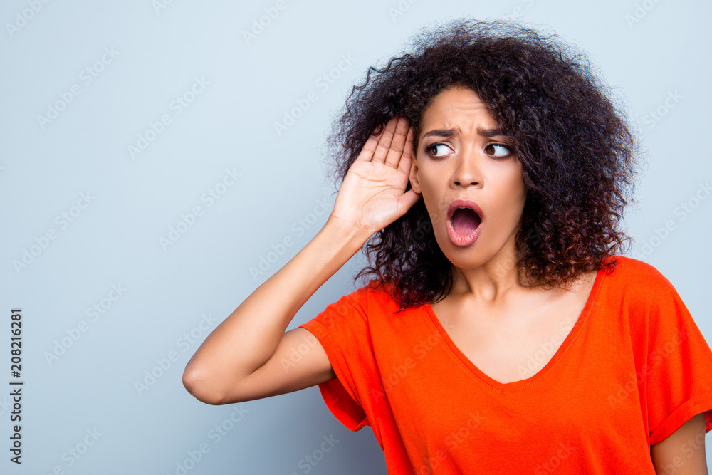 Portrait with copy space of shocked worried woman with wide open mouth holding hand near ear listening bad information gossips isolated on grey background Portrait with copy space of shocked worried woman with wide open mouth holding hand near ear listening bad information gossips isolated on grey background