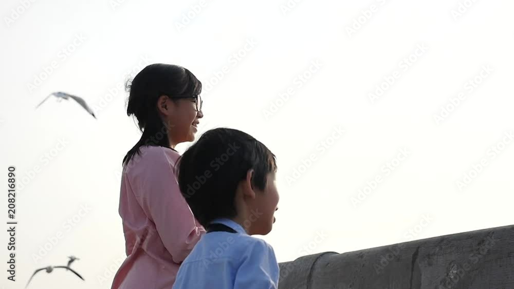 Asian children feeding the seagulls on the bridge, sunset time slow motion Asian children feeding the seagulls on the bridge, sunset time slow motion