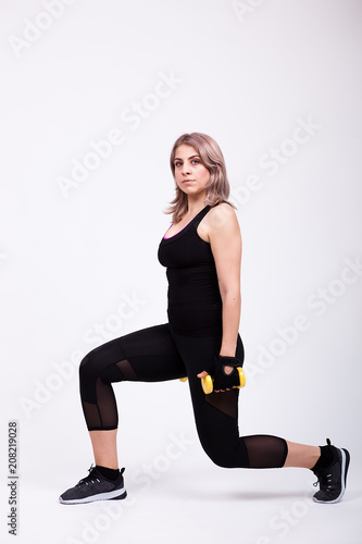 Woman exercising with two small dumbbells in studio photo. Full body image