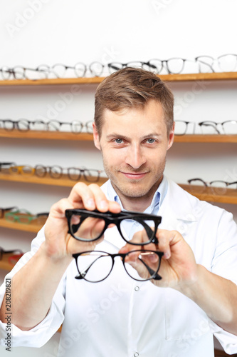 Twarzowe modne okulary. Mężczyzna wybiera oprawki okularowe w salonie optycznym