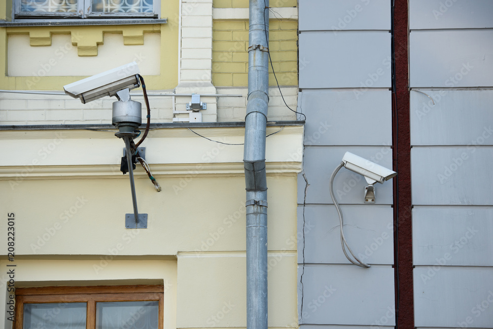 close up view of security cameras on different buildings facades close up view of security cameras on different buildings facades