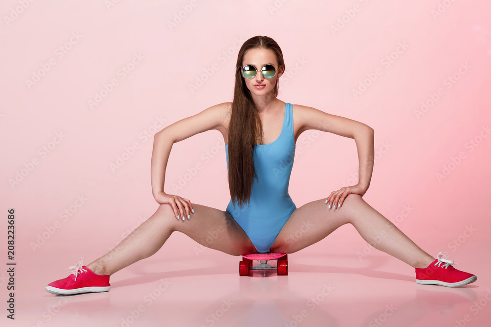 woman with skateboard on pink background