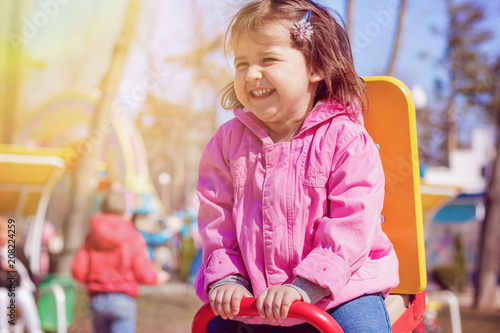 Little girl riding on swing and smiling and have fun on playground. Children's emotions