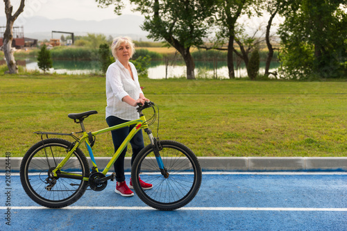 Senior woman stood with bicycle on track