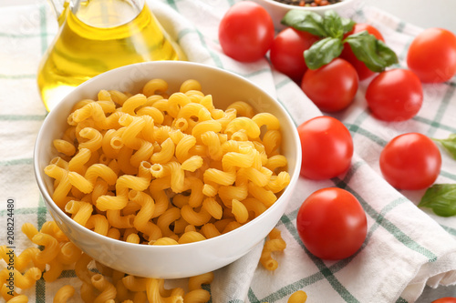 Bowl with uncooked pasta on table photo