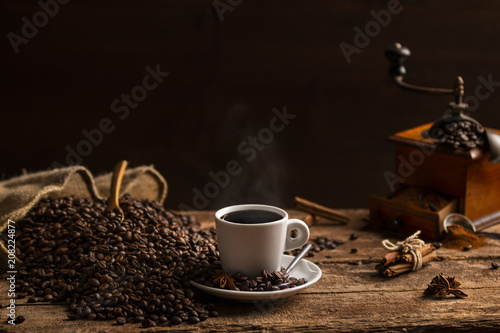 Cup of coffee with coffee beans and grinder on wooden table