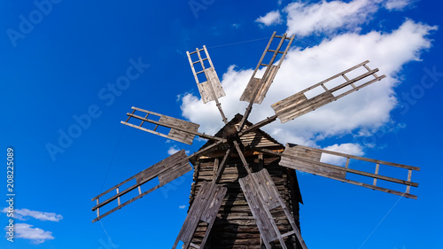 Old and broken wooden windmill against blue sky