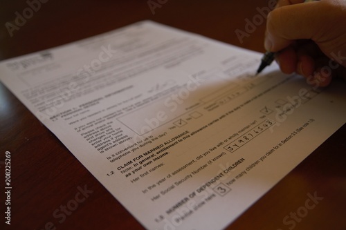 Hand filling out a tax form with pen